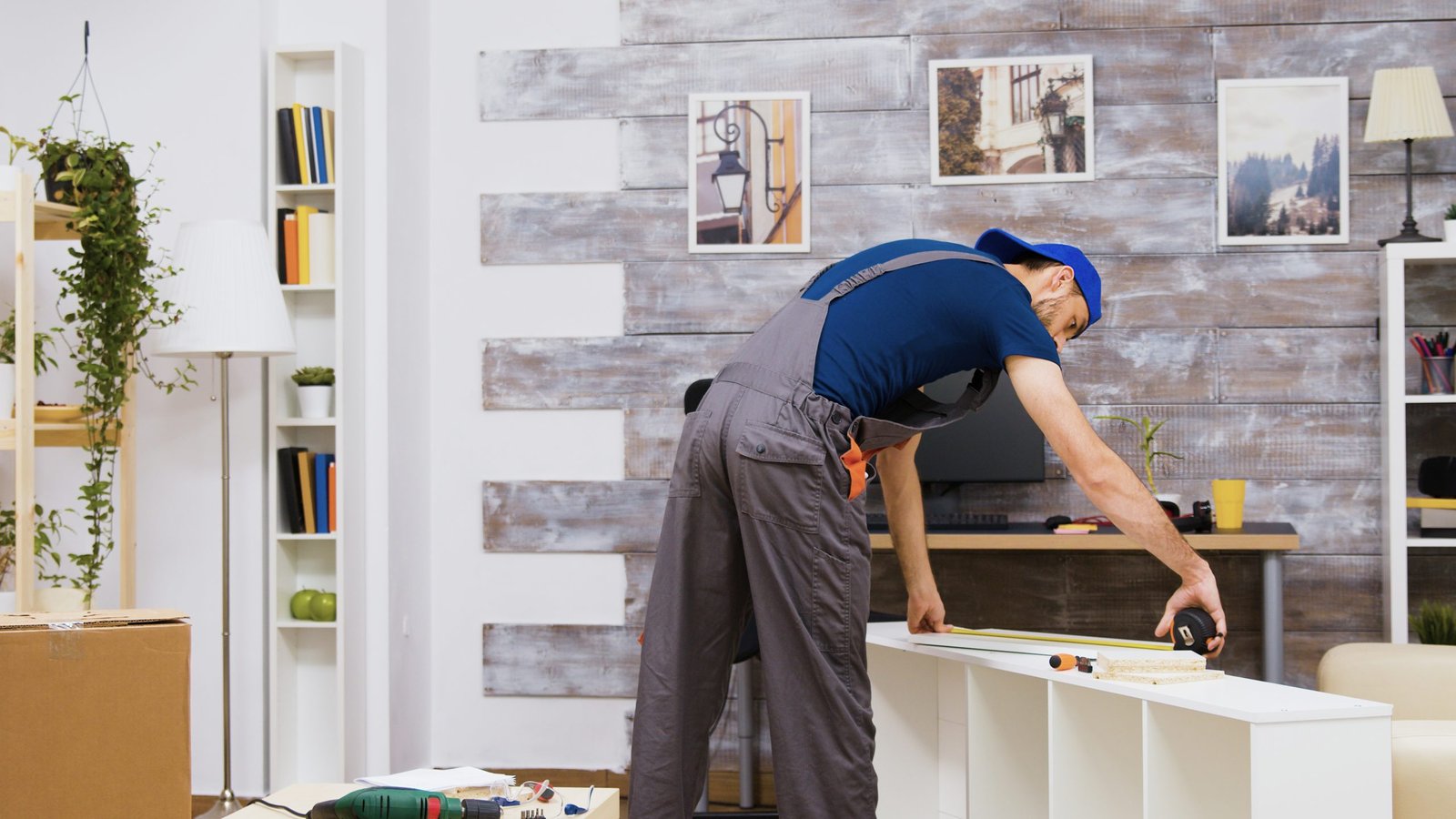 Furniture assembly worker standing reading instruction and using a tape measure. Worker tools.